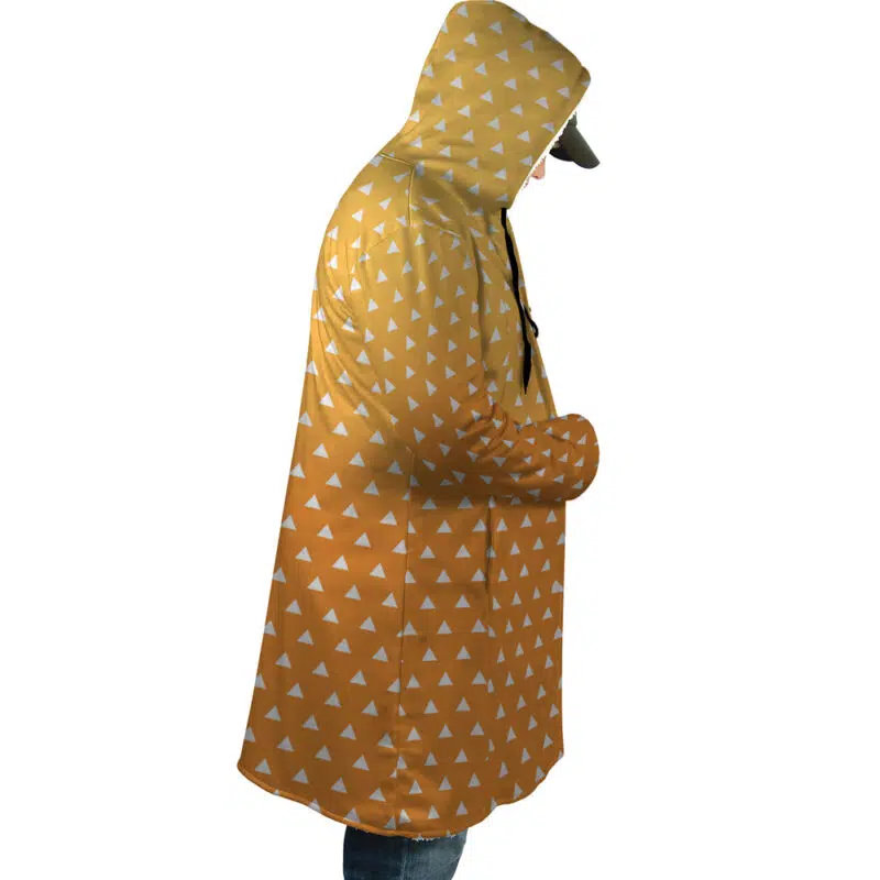 A person wearing the Zenitsu Agatsuma Demon Slayer Dream Cloak Coat—a long, hooded yellow-orange raincoat with a repeating white triangle pattern—viewed from the side against a plain white background.