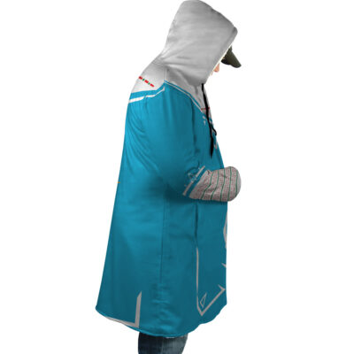 Wearing the Breath of Wild Zelda Dream Cloak Coat, a person with a blue and gray geometric hood stands in profile, looking down. They have a gray cap under the hood and hands tucked in the coat’s front pocket.