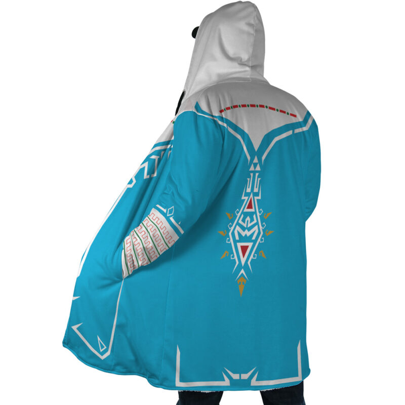 A person faces away from the camera wearing the Breath of Wild Zelda Dream Cloak Coat—a long blue hooded coat featuring white and red geometric designs inspired by fantasy or video game styles.