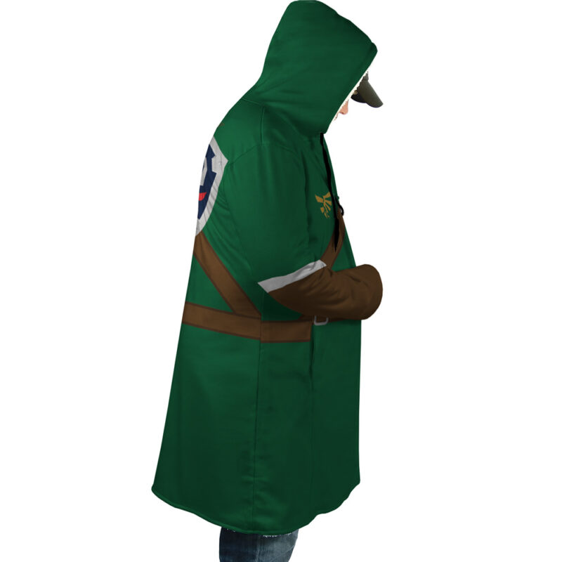 A person wearing the Link Zelda Dream Cloak Coat—a green hooded cloak with brown belts and a shield design on the back—stands sideways with head slightly bowed, resembling Link’s costume from The Legend of Zelda.