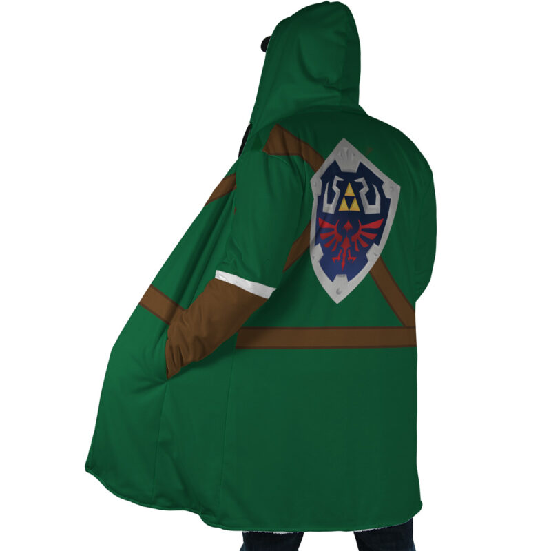 A person wears the Link Zelda Dream Cloak Coat, featuring a green hood, brown accents, and a prominent Hylian Shield design from The Legend of Zelda on the back while facing away to showcase the shield emblem.