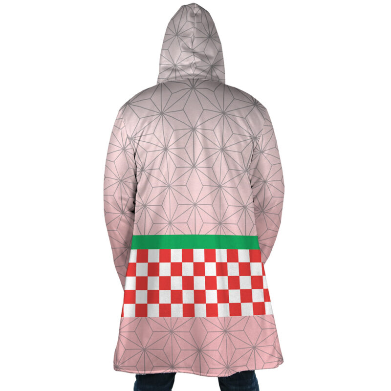 A person wearing the Nezuko Kamado Demon Slayer Dream Cloak Coat, featuring a geometric pattern, pinkish hues, a green horizontal stripe, and a red-and-white checkerboard design across the lower back.