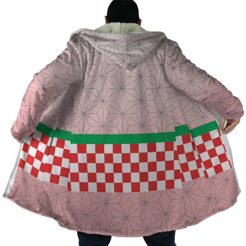 A person showcases the Nezuko Kamado Demon Slayer Dream Cloak Coat—a large, light pink coat with geometric patterns, a green stripe, and a red-and-white checkerboard design on the lower back—by holding it open.