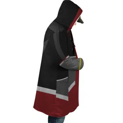 A person in profile wears the Sora Kingdom Hearts Dream Cloak Coat, featuring a black, gray, and maroon color block design with a hood over a cap. Their hands are tucked inside the cloak.