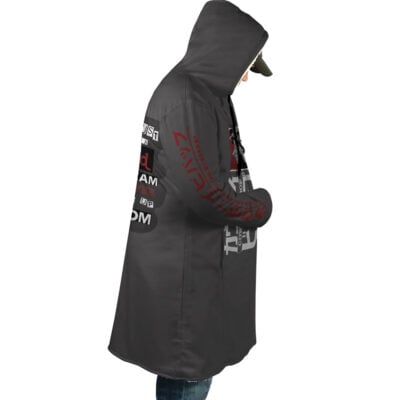 A person wearing the Spiegel Spike 2 Dream Cowboy Bebop Dream Cloak Coat featuring printed graphics and text on the back and sleeves stands sideways, looking downward, paired with a cap and jeans.