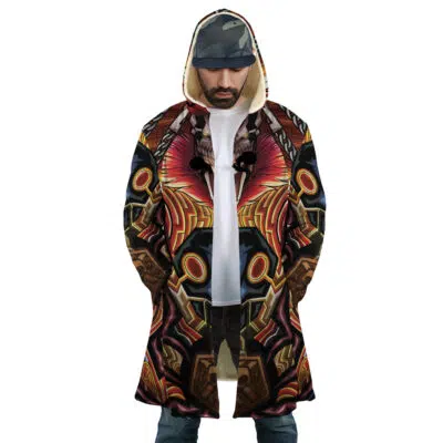 A man wears the Ichigo True Shikai Bleach Dream Cloak Coat—featuring bold red, black, brown, and gold patterns—hood up, hands in pockets, looking down, and wearing a cap.