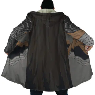 A person wearing the Guts Armor Berserk Dream Cloak Coat, featuring a printed metallic armor design with brown straps, is shown from the back with arms outstretched to display the full pattern.