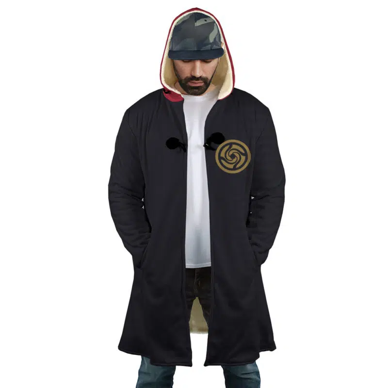 A man wearing the Yuji Itadori Jujutsu Kaisen Dream Cloak Coat with a light lining and gold circular chest emblem, paired with a white t-shirt, blue jeans, and a patterned cap, looks down.