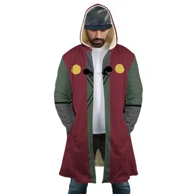 A man wearing the Jiraiya Uniform Shippuden Dream Cloak Coat, a long hooded coat with maroon, olive green, and gray panels, yellow accents, and black chest cords. He pairs it with a white t-shirt, blue jeans, and a patterned cap.