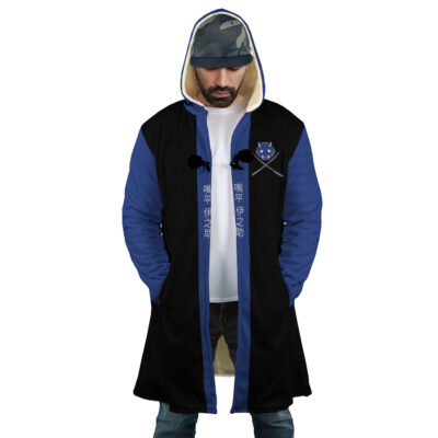 A man wearing the Hashibira Inosuke Demon Slayer Dream Cloak Coat, a blue and black hooded coat with fur lining, crossed swords and a crest on the chest, and white Asian script down the front. He looks down while wearing a cap.