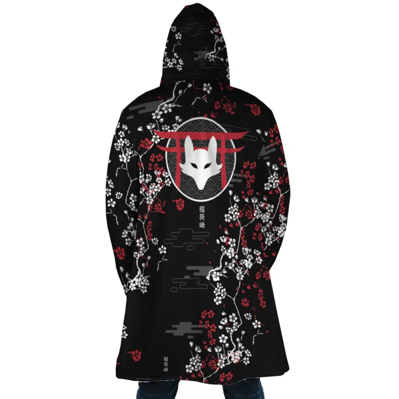 Someone wearing the Inarizaki Foxes Haikyuu Dream Cloak Coat, featuring a black hood, a white fox mask design on the back with red and white plum blossoms, stylized clouds, and Asian characters printed below the mask and near the hem.