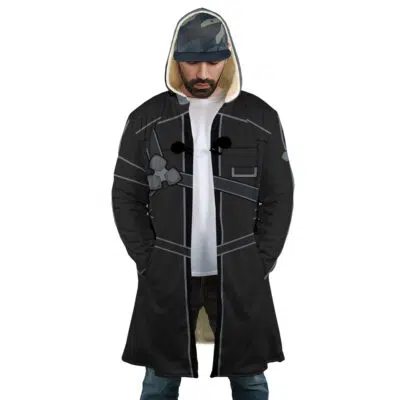 A man wearing the Kirito Sword Art Online Dream Cloak Coat over a white t-shirt, blue jeans, and a dark cap stands with his hands in his coat pockets, looking down.