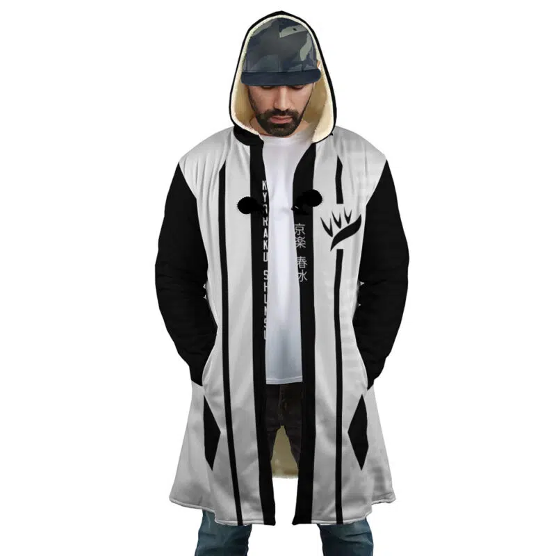 A man wears the Gotei 13 8th Division Captain Kyoraku Shunsui Bleach Dream Cloak Coat, featuring a hood, white front, black sleeves, and black vertical stripes. His hood is up and hands are in his pockets; Asian characters appear on his shirt.