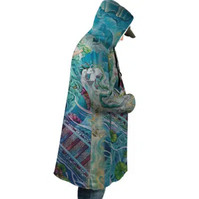 Someone in profile wears the Mythical Spirited Away Studio Ghibli Dream Cloak Coat—a colorful, hooded coat with detailed fantasy art of a white dragon, swirling blue waves, and decorative accents. They have hands in pockets and are paired with jeans.
