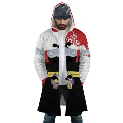 A man wears the Sesshomaru Inuyasha Dream Cloak Coat—a hooded, knee-length piece with bold red, white, black, yellow, and purple designs. He looks down with his hands in his pockets, a blue cap visible under the hood.