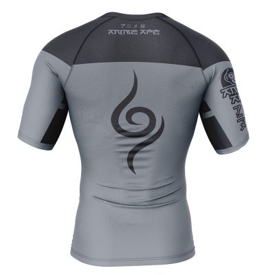 The Kakashi Anbu Shippuden Short Sleeve Rash Guard Compression Shirt is a fitted grey athletic top with black accents, bold spiral on the back, Japanese text on upper back and right sleeve, plus a stylized patch on the left sleeve.