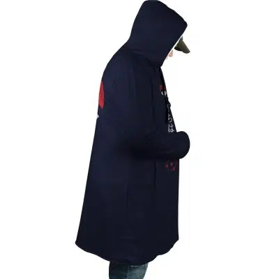 A person stands in profile with hands in pockets, wearing the Uchiha Clan Sharingan Shippuden Dream Cloak Coat and a cap, set against a white background.