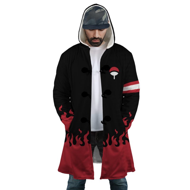 A man wears the Uchiha Clan Shippuden Dream Cloak Coat: black and red with flame designs at the hem and sleeves, a white clan symbol on the chest, striped armband, hood up, and a plain white shirt underneath.