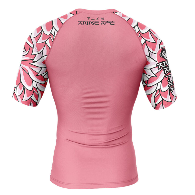 The Doflamingo One Piece Short Sleeve Rash Guard Compression Shirt is a fitted pink athletic top with floral petal designs on the sleeves and upper back, featuring ANIME APE and Japanese characters printed in black on the back.