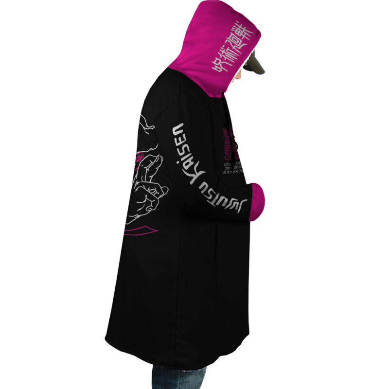 A person in the Pink Gojo Jujutsu Kaisen Dream Cloak Coat, featuring black with pink and white graphics, Japanese text, "Jujutsu" on the sleeve, and a pink hood with more Japanese characters, is shown facing sideways.