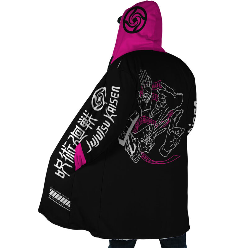 A person faces away from the camera wearing the Pink Gojo Jujutsu Kaisen Dream Cloak Coat, a black and pink hooded cloak with bold white and pink graphics, Japanese text, "Jujutsu Kaisen," and stylized hand designs on the back.