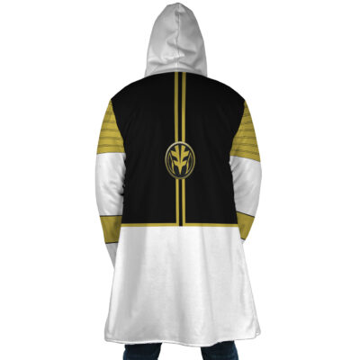 A person stands with their back to the camera wearing the White Ranger Mighty Morphin Power Rangers Dream Cloak Coat, featuring a black, white, and gold design with a bold emblem on the back and gold shoulder stripes.
