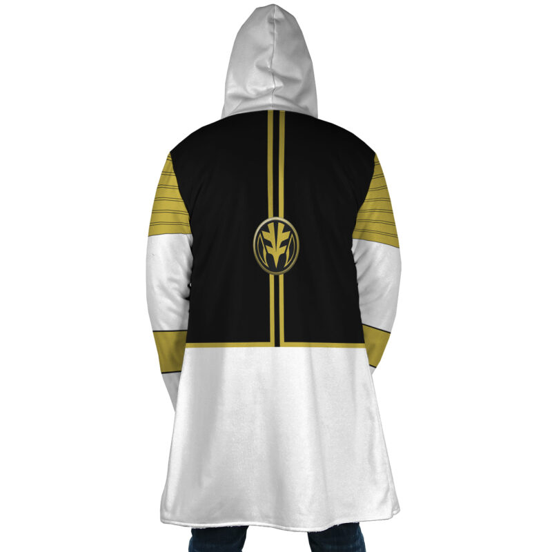 A person stands with their back to the camera wearing the White Ranger Mighty Morphin Power Rangers Dream Cloak Coat, featuring a black, white, and gold design with a bold emblem on the back and gold shoulder stripes.