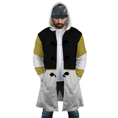 A man wearing the White Ranger Mighty Morphin Power Rangers Dream Cloak Coat, featuring black, white, and olive green sections with decorative black buttons, stands with hands in pockets and head slightly bowed.
