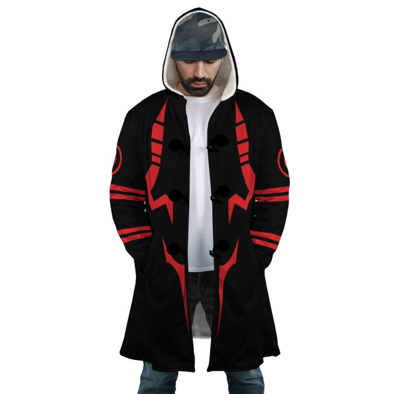 A man wearing the Sukuna Jujutsu Kaisen Dream Cloak Coat with bold red geometric patterns, a white shirt, jeans, and a camouflage cap stands with hands in pockets, looking slightly downward.