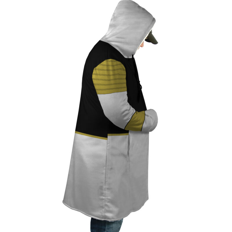 A person wearing the White Ranger Mighty Morphin Power Rangers Dream Cloak Coat, a hooded long coat with black, gray, and gold color blocks, stands in profile with hands in pockets, showcasing its casual modern design.