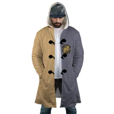 A man wears the Hogwarts Legacy Hufflepuff Harry Potter Dream Cloak Coat, a long hooded coat divided tan on the left and gray on the right, with black toggle buttons, a gold chest emblem, and his hands in the pockets.