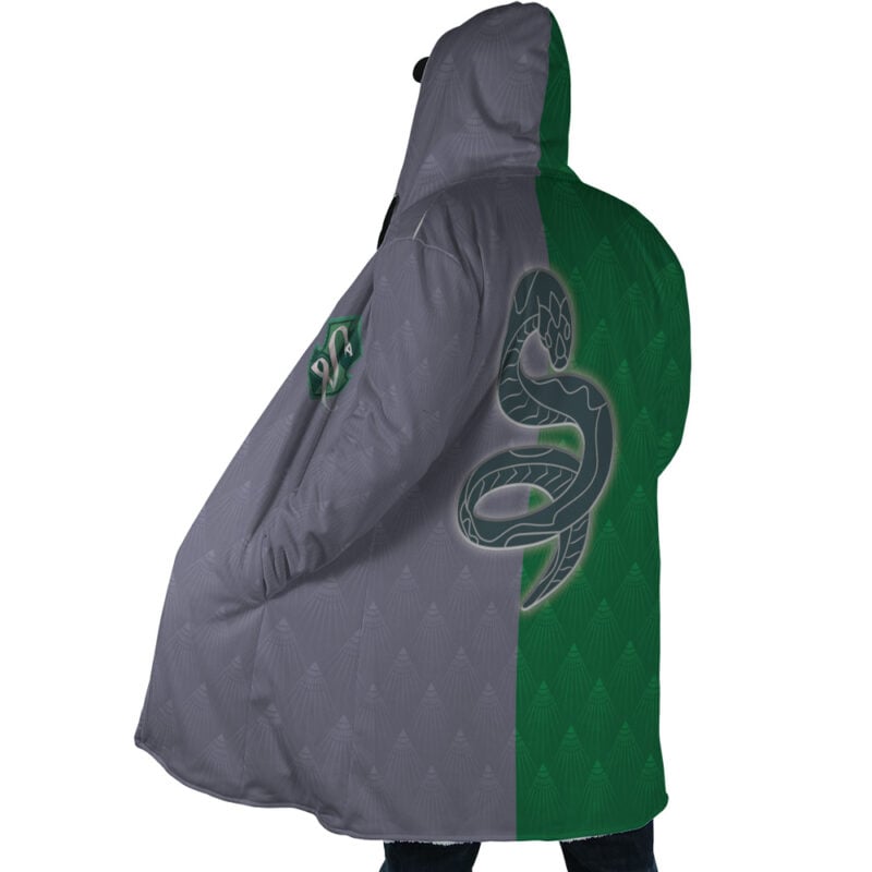 A person wears the Hogwarts Legacy Slytherin Harry Potter Dream Cloak Coat, featuring a split gray and green design, a large snake emblem on the back, and a Slytherin patch on the sleeve.