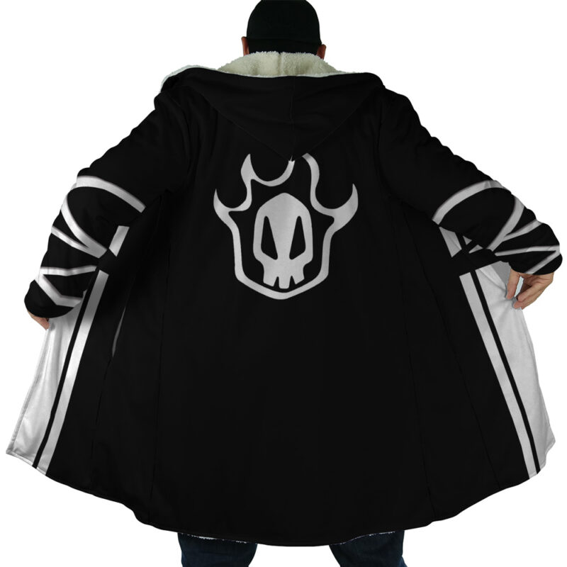 Someone wears the Ichigo Kurosaki Bleach Dream Cloak Coat, a long black coat with white trim and a large skull-like flame emblem on the back, holding it open to display the design. Their face is not visible.