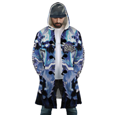 A man wears the Trippy The Shadow Monarch Solo Leveling Dream Cloak Coat, featuring blue and black patterns with Solo Leveling text on the chest, hands in pockets, looking down, and a cap under his hood.