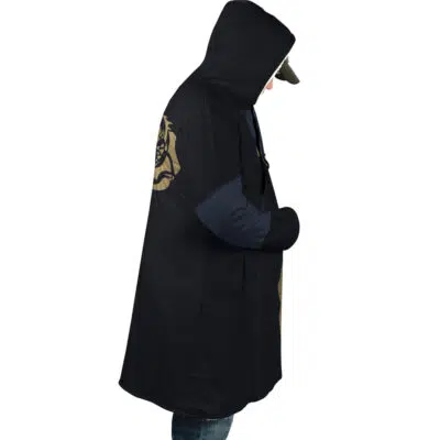 In profile view, a person wears the Rimuru Tempest That Time I Got Reincarnated as a Slime Dream Cloak Coat—long, black with gold accents on sleeve and back—blue sleeves and jeans beneath, cap under hood, and hands in coat pockets.