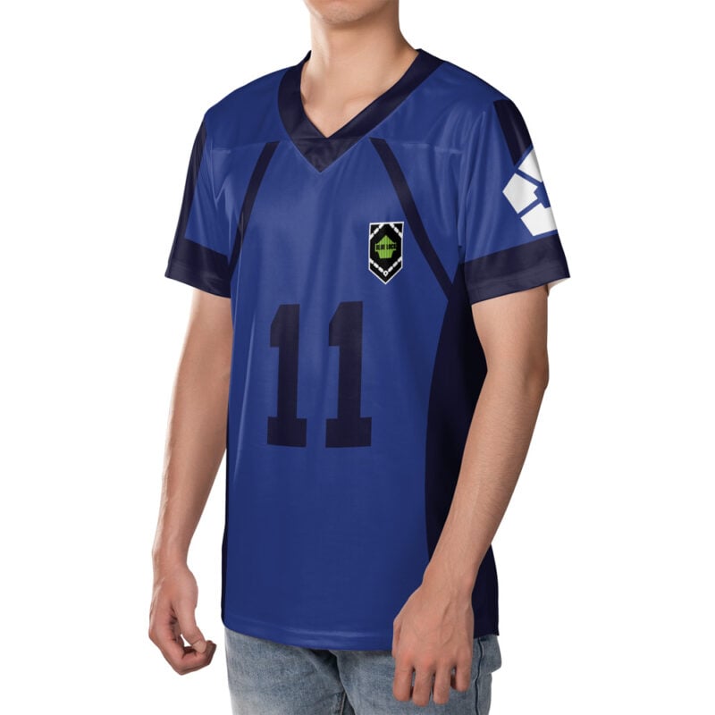 A person wears the Yoichi Isagi FC Blue Lock Soccer Jersey—blue with black accents, number 11, a green and black shield logo on the chest, and a white geometric design on the right sleeve. Theyre in jeans and partially visible.