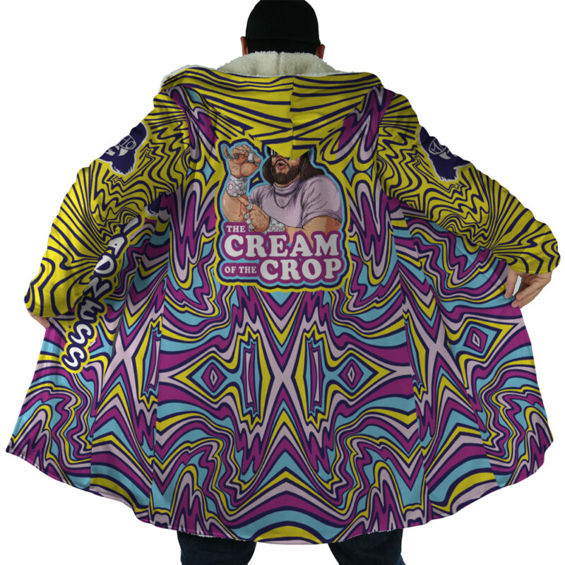 A person wears the Trippy The Cream of the Crop Randy Savage Dream Cloak Coat, featuring bold purple, yellow, and blue psychedelic swirls and a back illustration of a bearded man with a creamer cup and “THE CREAM OF THE CROP” caption.