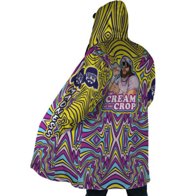 A person wears the Trippy The Cream of the Crop Randy Savage Dream Cloak Coat, a vibrant hooded cloak with swirling yellow, purple, and blue patterns featuring a bearded man in sunglasses and Cream of the Crop text.