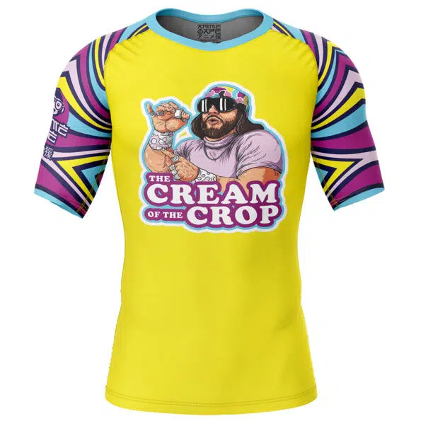 The Cream of the Crop Trippy Randy Savage Short Sleeve Rash Guard Compression Shirt features a bright yellow color, colorful geometric sleeves, and a cartoon wrestler with sunglasses and headband on the front.