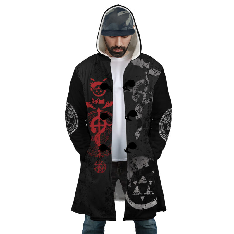 A man wears the Transmutation Circle Fullmetal Alchemist Dream Cloak Coat—a long black hooded coat with red and white alchemy symbols—standing hands in pockets, looking down, with a cap under his hood.