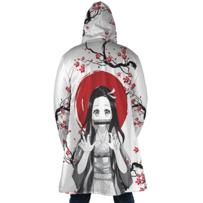 A person wearing the Nezuko Kamado Cherry Blossom Demon Slayer Dream Cloak Coat, which features anime art of a girl with long hair, a bamboo gag, a red sun, and cherry blossom branches in the background.