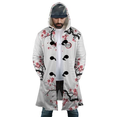 A man wears the Nezuko Kamado Cherry Blossom Demon Slayer Dream Cloak Coat, featuring a hood, black and red cherry blossom branch design, large black toggle buttons, and a Demon Slayer patch. He stands with hands in pockets, looking down.
