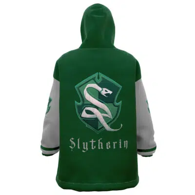 The Slytherin Hogwarts Legacy Snug Oversized Blanket Hoodie is green with gray sleeves, a large Slytherin crest and snake emblem on the back, and "Slytherin" written below the crest in a stylized font.