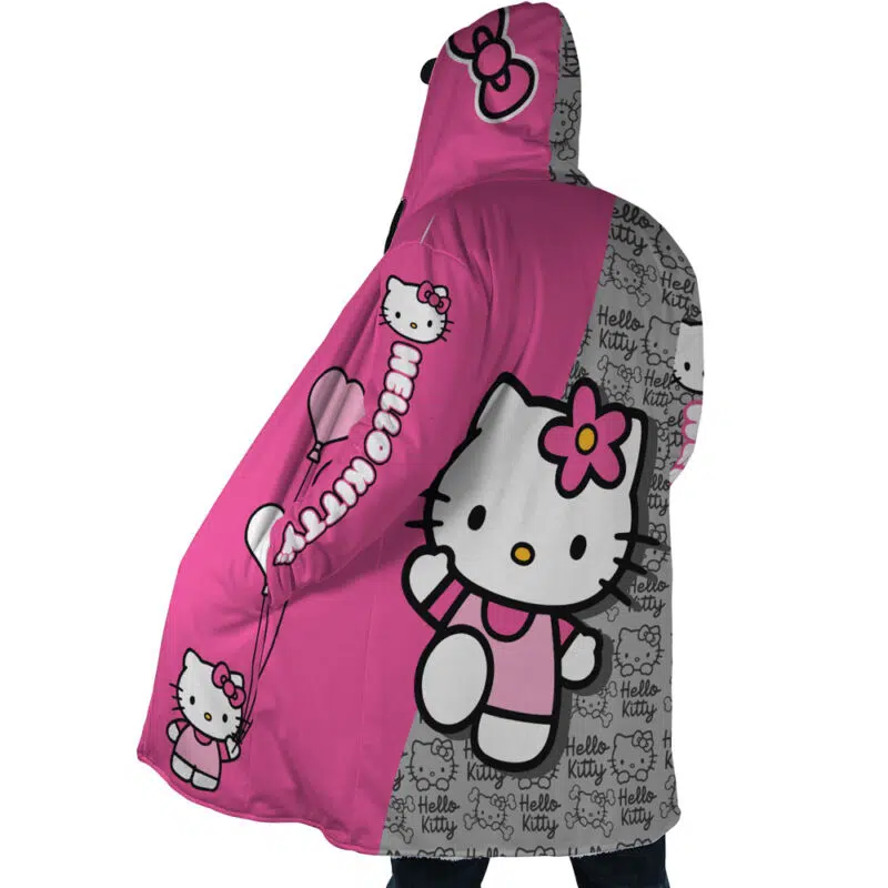 A person wearing the Hello Kitty Sanrio Dream Cloak Coat, a hooded blanket in pink and gray with large Hello Kitty images, hearts, and "Hello Kitty" text repeated across the fabric.