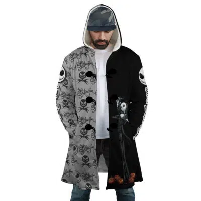 A man wears the Jack Skellington The Nightmare Before Christmas Dream Cloak Coat, a long hooded coat that's half gray with Jack Skellington faces and half black with a large Jack image and small pumpkins at the bottom.