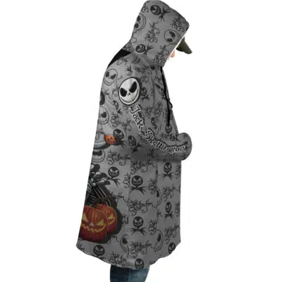 A person wearing the Jack Skellington The Nightmare Before Christmas Dream Cloak Coat, featuring a gray design with Jack Skellington, black bats, and orange pumpkins, faces sideways with their head slightly bowed.