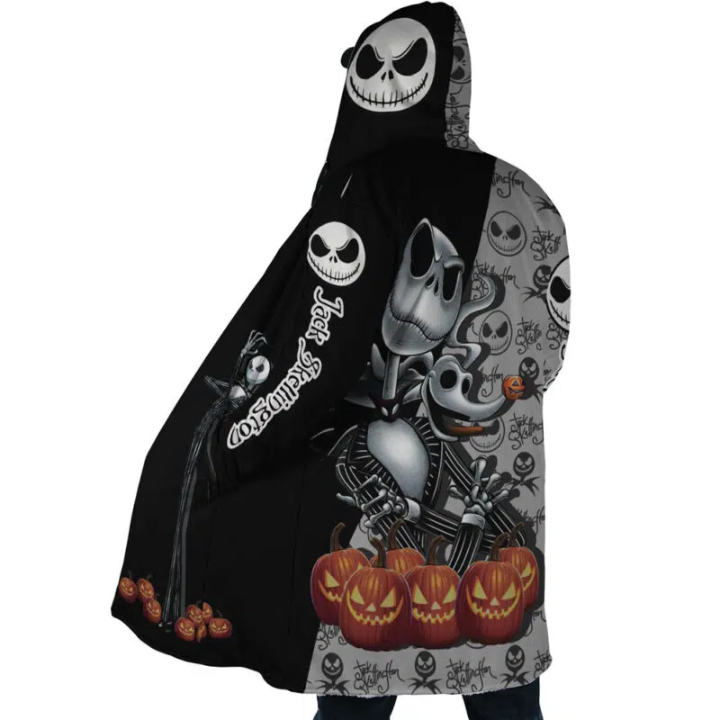 A person wears the Jack Skellington The Nightmare Before Christmas Dream Cloak Coat, a hooded jacket with Halloween-themed art of Jack Skellington, Zero the ghost dog, and smiling jack-o’-lanterns, featuring black and gray panels.