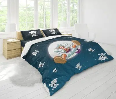 The Gear 5 Luffy v2 One Piece Bedding Set features bold blue bedding with cartoon astronaut goat and star designs, plus small skull accents. The room is bright, with large windows, white walls, and light wood furniture.