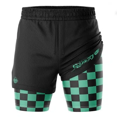 The Tanjiro Kamado Demon Slayer Performance Shorts feature black athletic shorts with an overlapping layer that reveals green and black checkered compression shorts, plus turquoise Japanese text and a small outer logo.
