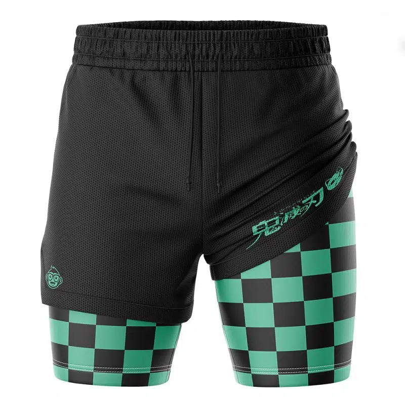 The Tanjiro Kamado Demon Slayer Performance Shorts feature black athletic shorts with an overlapping layer that reveals green and black checkered compression shorts, plus turquoise Japanese text and a small outer logo.